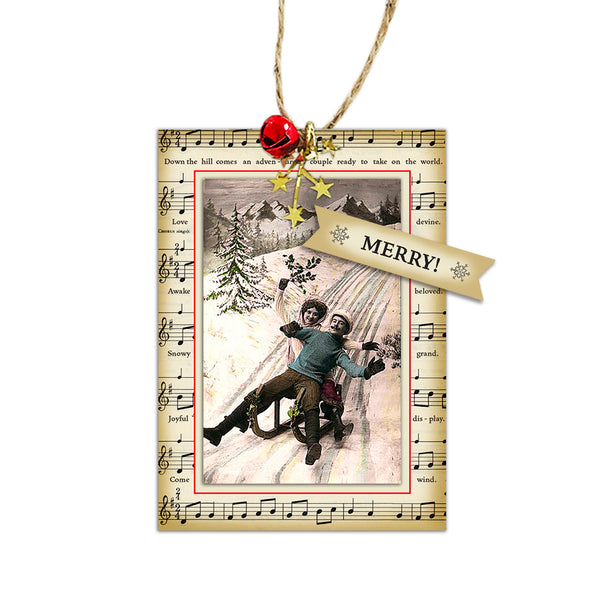 Check out our Victorian couple coming down the hill in a “let’s celebrate” fashion. Reduced French Vintage New Year’s post card mounted onto a reduced vintage music sheet. Red jingle bell and gold star garland accent jute twine hanger. French Victorian sledding photo comes forward with three paper layers separated by foam lifts. Victorian Christmas tree ornaments using funny Victorian photos. Perfect as a gift topper and humorous conversation piece.  tribegift.com
